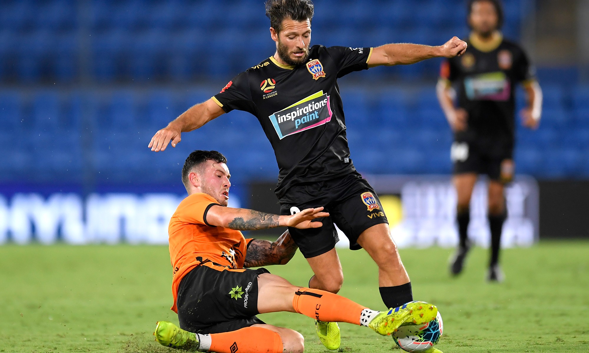 Brisbane Roar's Aiden O'Neill tackles Newcastle Jets marquee man Wes Hoolahan.