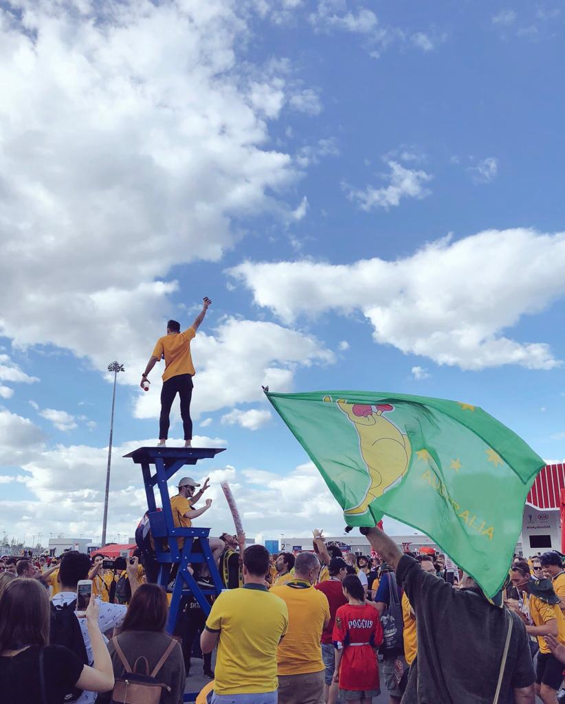 An Aussie stands above many Aussie fans leading chants