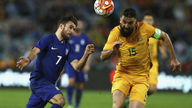Caltex Socceroos skipper Mile Jedinak vies for the ball with Greek forward Giannis Gianniotas.