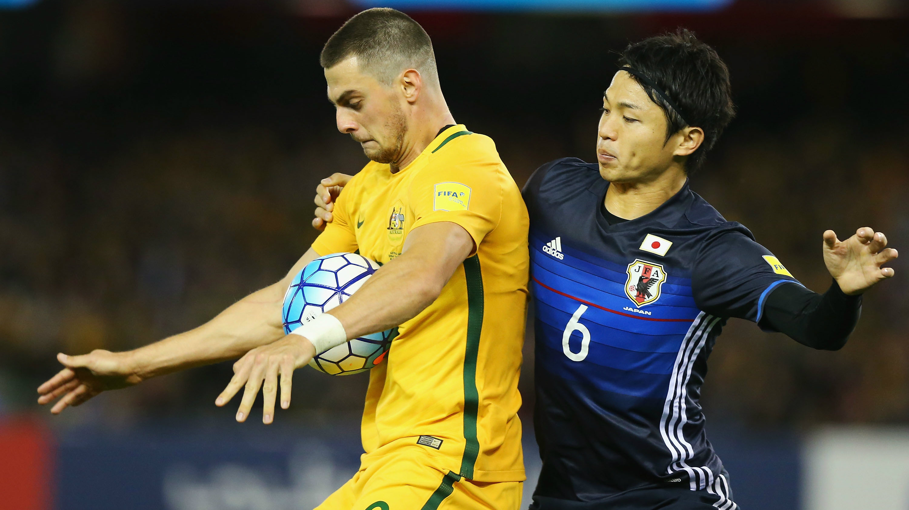Tomi Juric of the Socceroos and Masato Morishige of Japan compete for the ball.