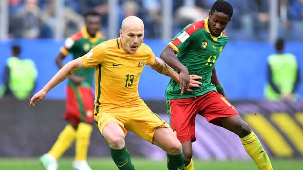 Caltex Socceroos midfielder Aaron Mooy holds off a Cameroon defender.