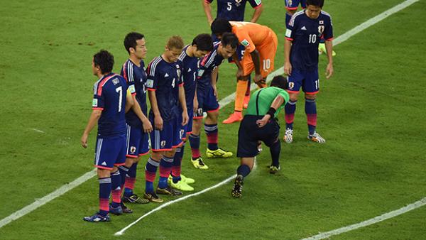 The referee sprays a temporary line for a freekick defended by Japan at the World Cup.