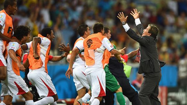 Costa Rica players celebrate with coach Jorge Luis Pinto after their third goal against Uruguay.