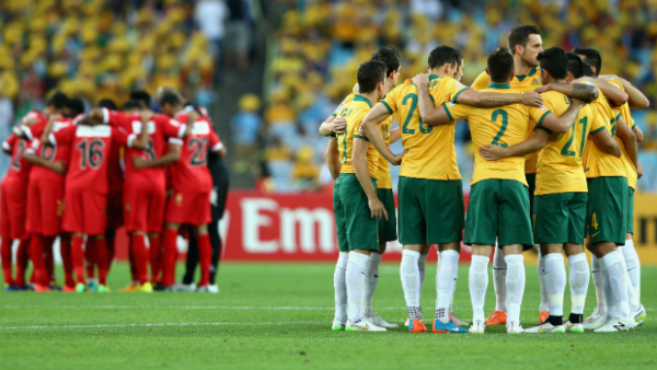 The Socceroos and Oman starting XI's form a huddle prior to kick-off at Stadium Australia.
