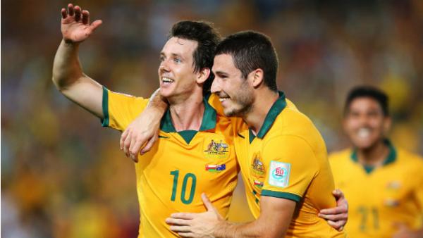 Robbie Kruse celebrates scoring against Oman with teammate Mathew Leckie.