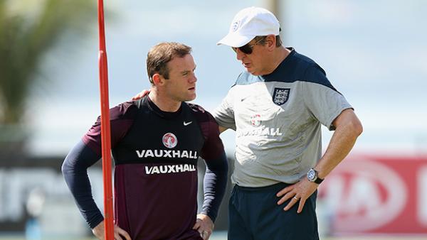 England striker Wayne Rooney receives advice from coach Roy Hodgson at training.