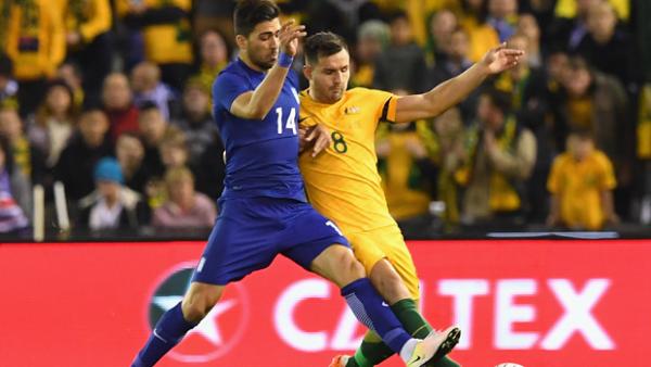 Bailey Wright challenges for the ball with Greek forward Anastasios Bakasetas.