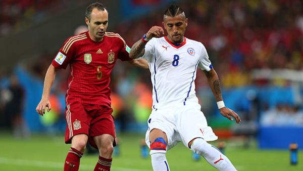 Vidal challenges for the ball with Spain's Andres Iniesta.